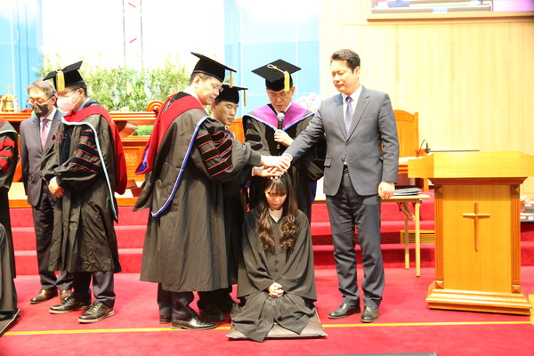 가르쳤던 교수들이 졸업자들에게 안수례를 베풀고 있다.