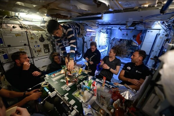 다양한 음식으로 분위기 있는 만찬 중인 우주선 내 승선원들